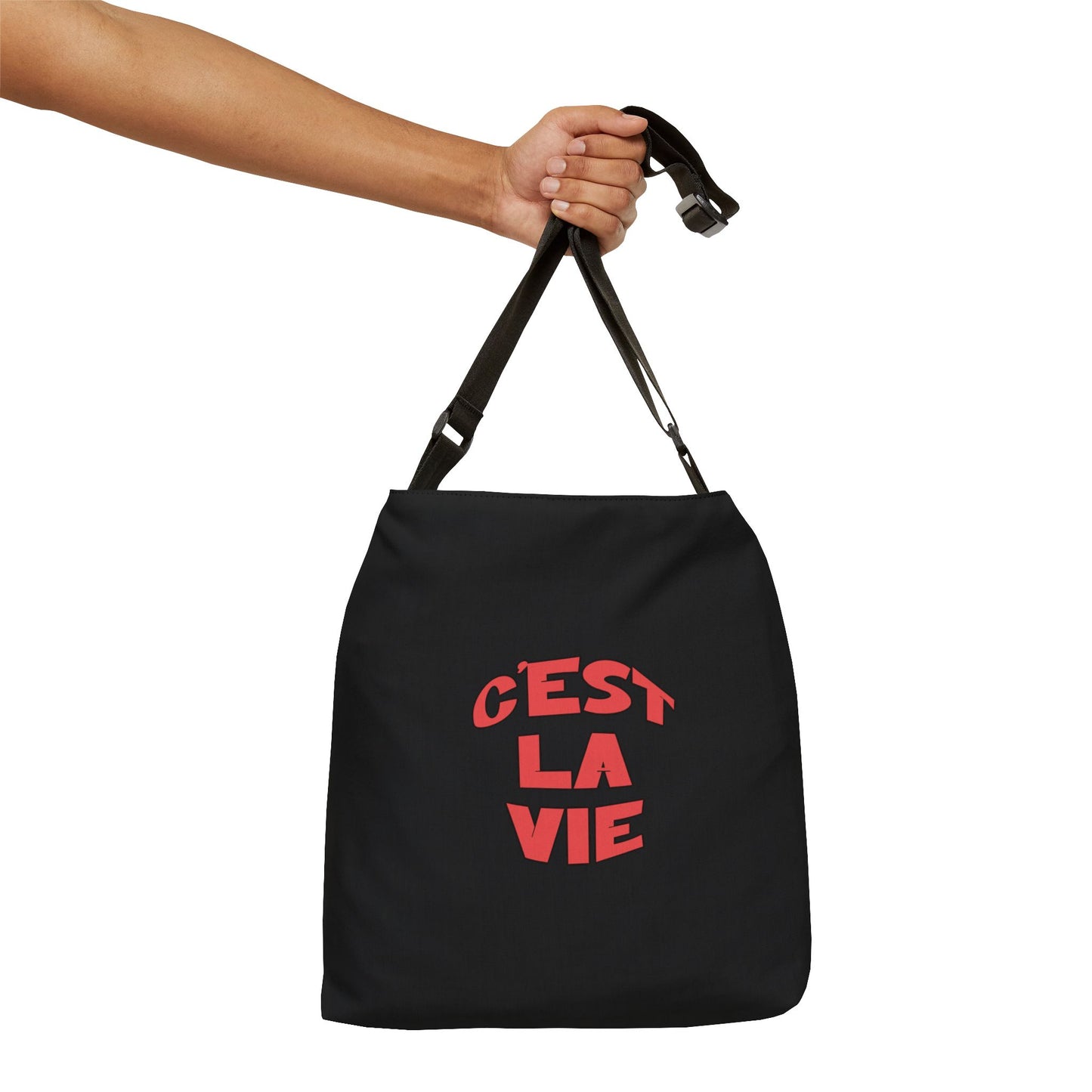 Black bag with 'Cést La Vie' text held by a hand on a white background