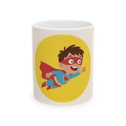 A white ceramic mug featuring a cartoon illustration of a young boy dressed as a superhero flying in front of a yellow oval on the front.