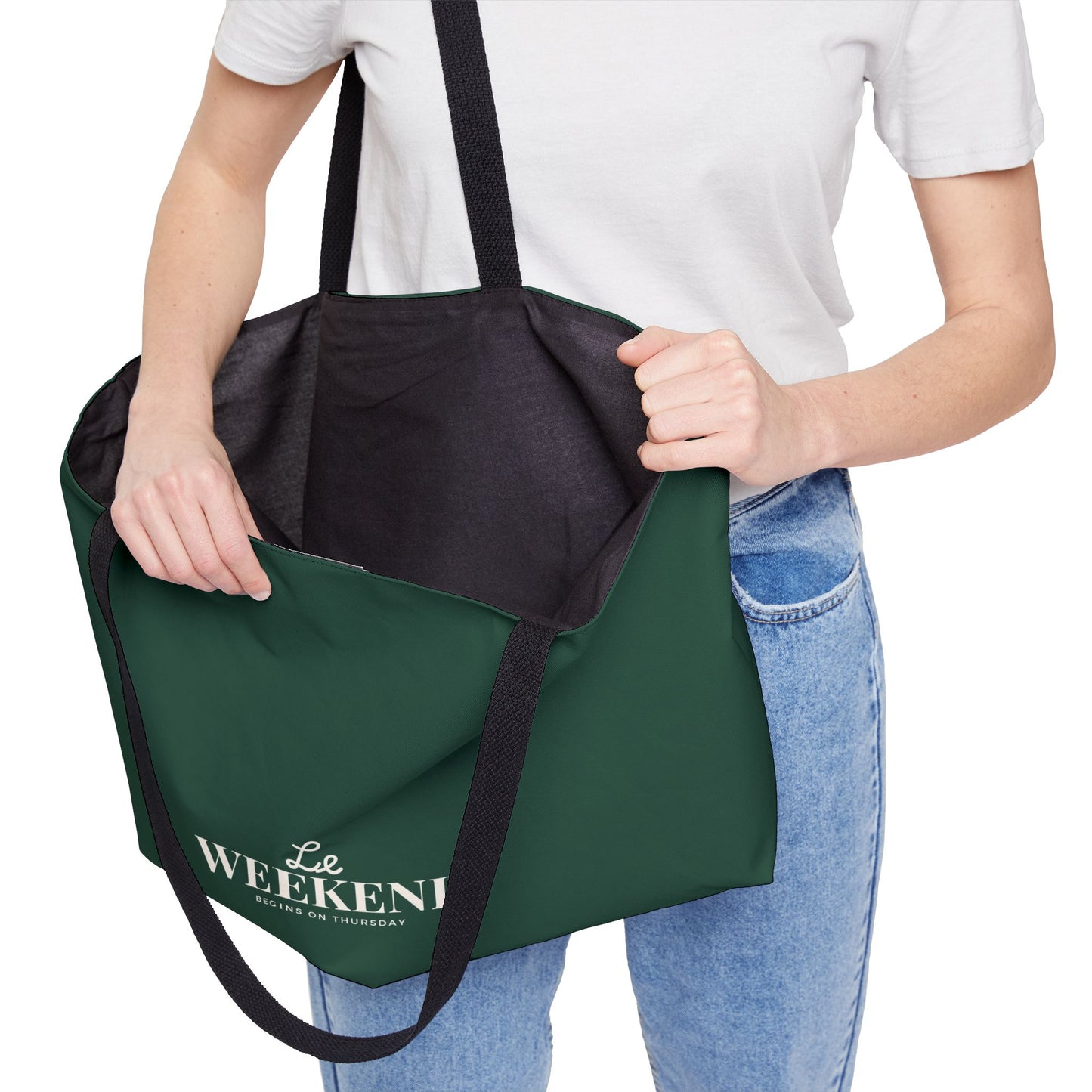 Green tote bag with black interior pocket held by a person wearing a white shirt and blue jeans.