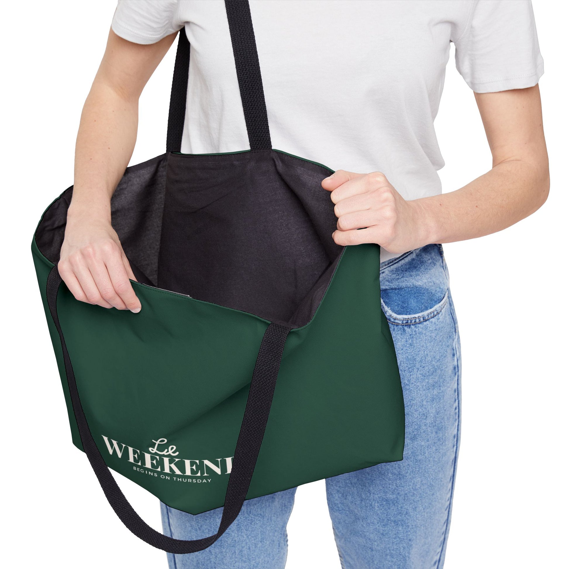 Green tote bag with black interior pocket held by a person wearing a white shirt and blue jeans.