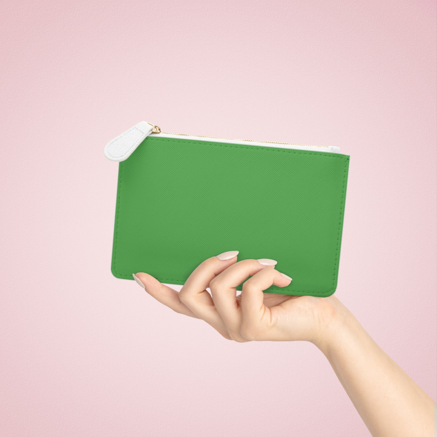 Hand holding a green pouch against a pink background
