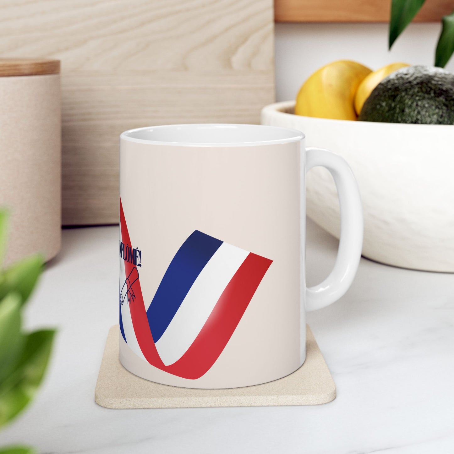 White mug with red and blue design on a coaster, placed on a light surface with a blurred background.