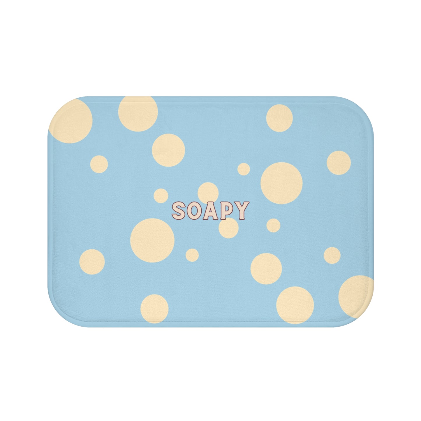 A rectangular bath mat with rounded corners in a light blue color, decorated with scattered beige polka dots and the word 'SOAPY' printed in the center.