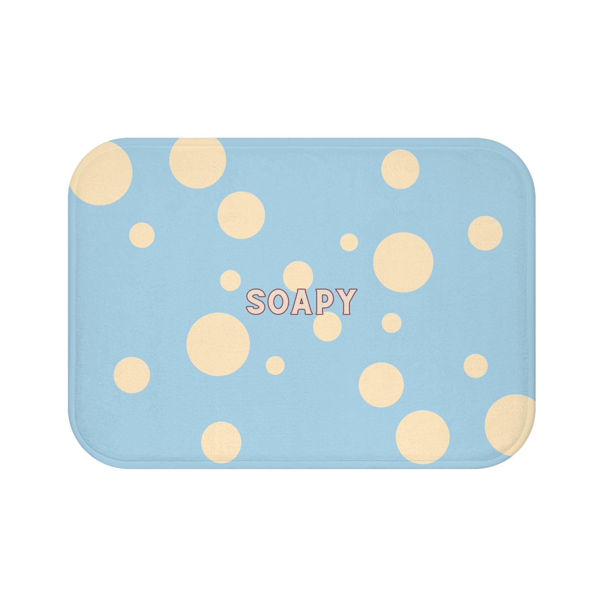 A rectangular bath mat with rounded corners in a light blue color, decorated with scattered beige polka dots and the word 'SOAPY' printed in the center.