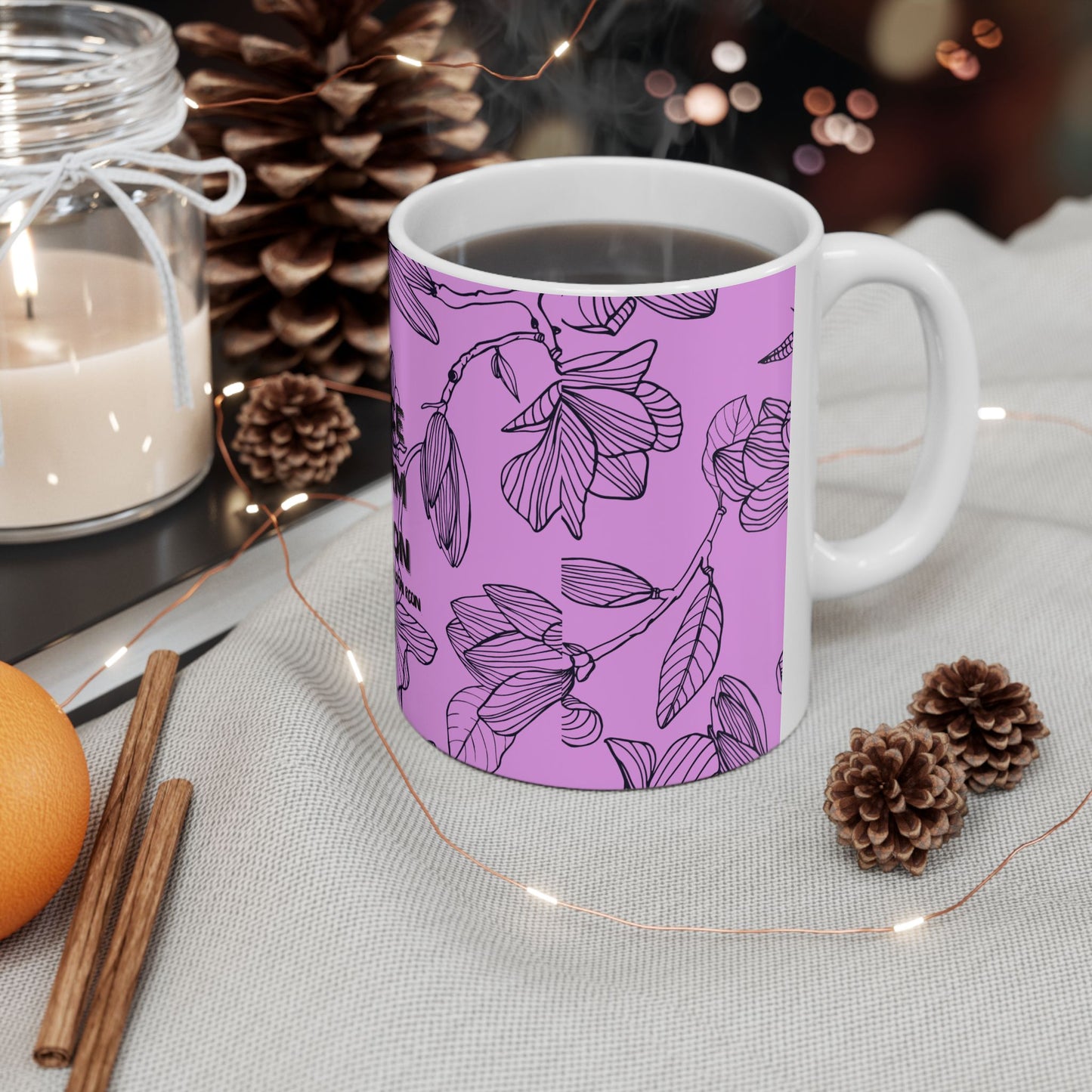 White mug with purple floral pattern on a table with decorative items