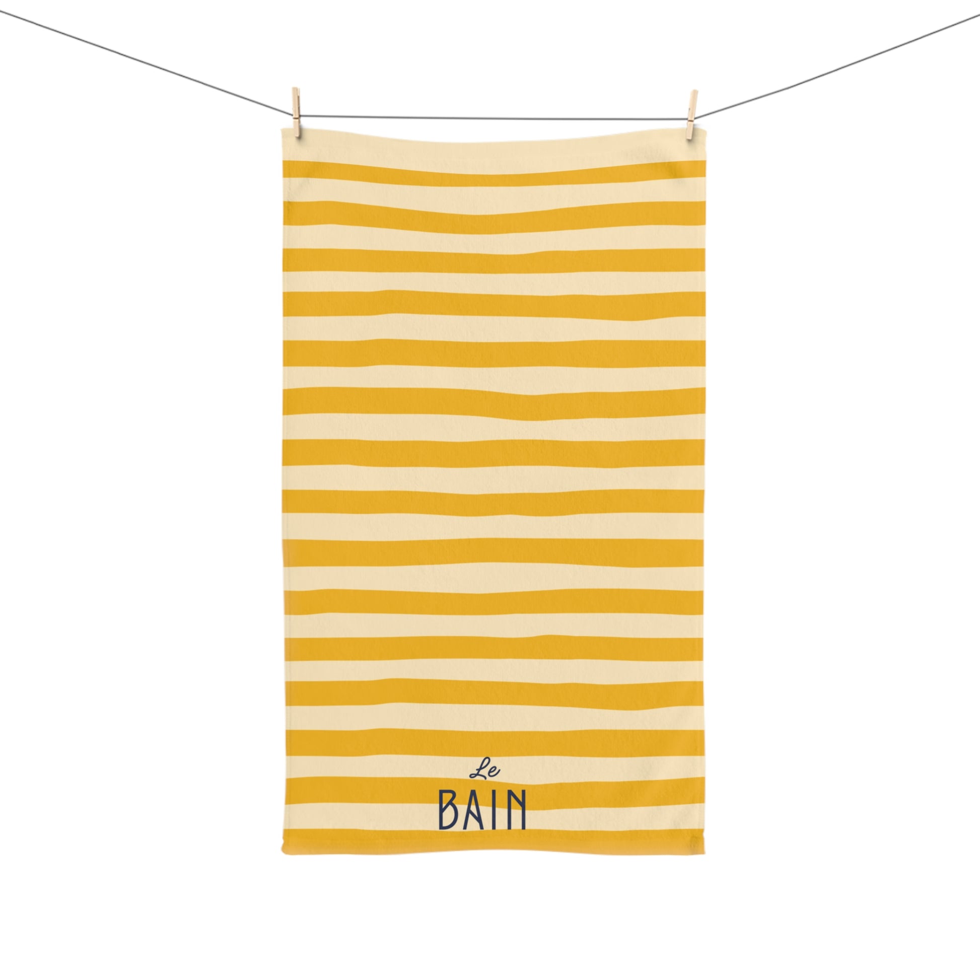 Yellow and white striped towel with 'Le Bain' text hanging on a line.