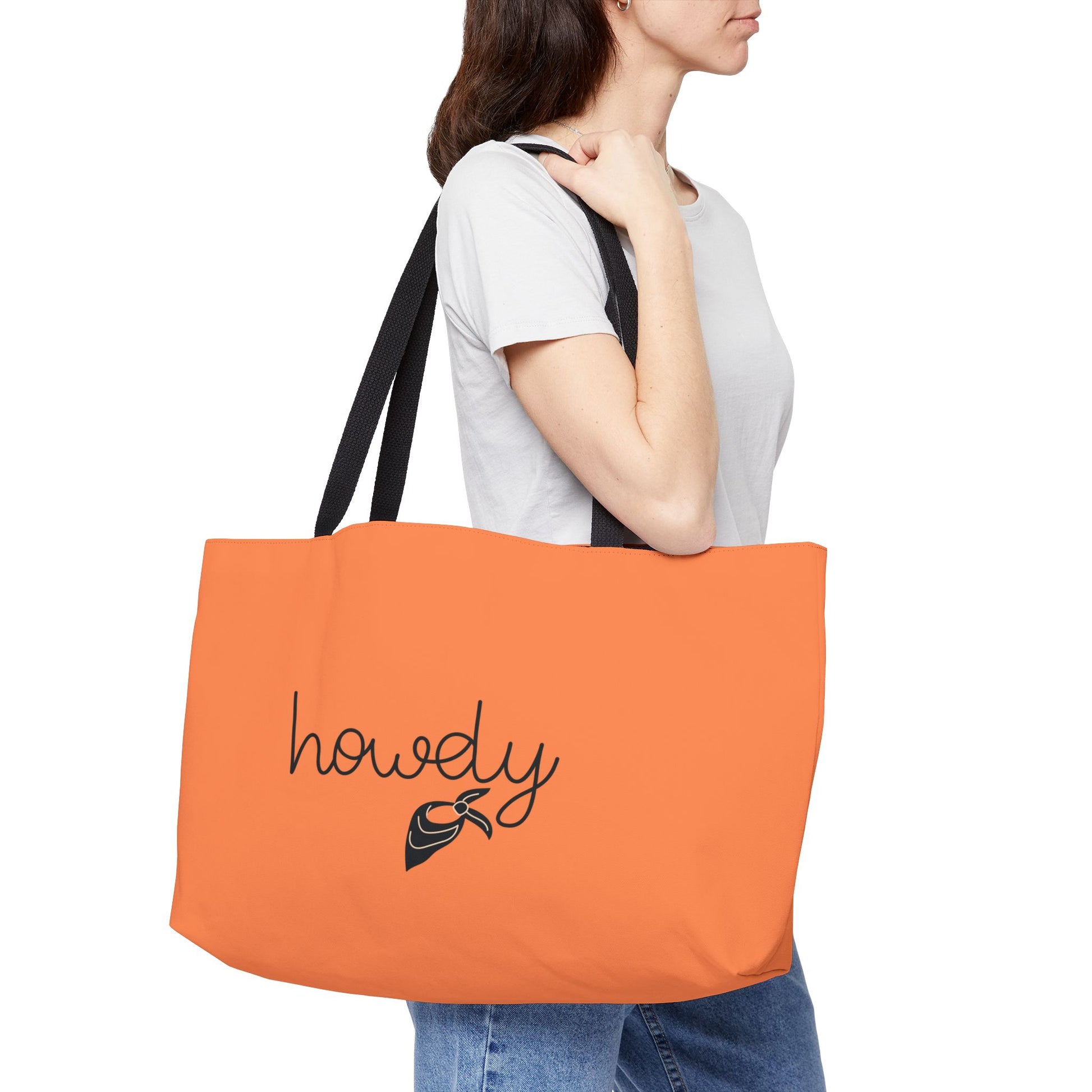 Person holding an orange tote bag with 'howdy' text and logo.
