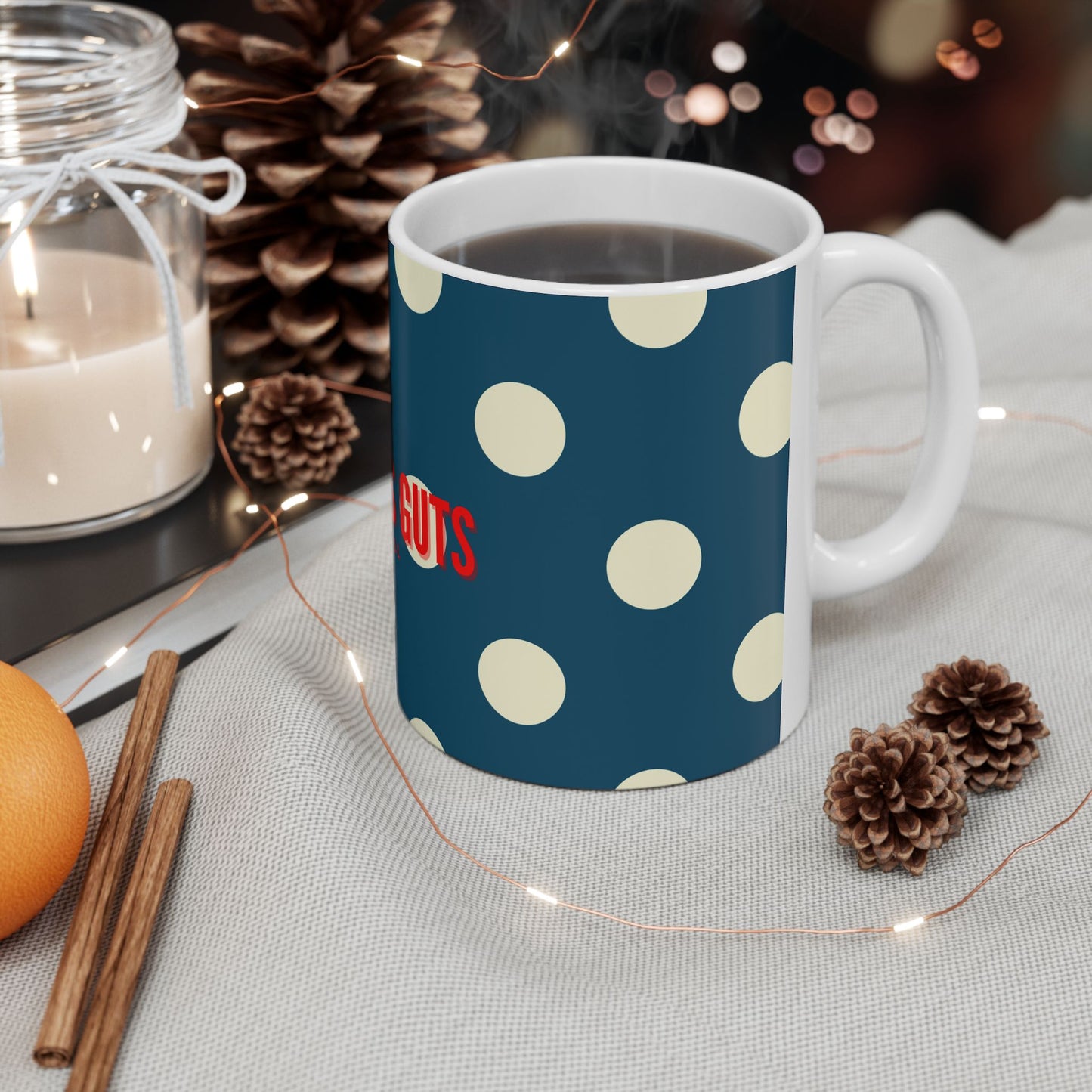 Mug with polka dot pattern and 'SUTS' text on a table with decorative items