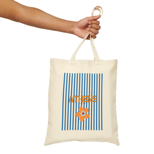 Tote bag with 'Athens' and a flower design held by a hand on a white background