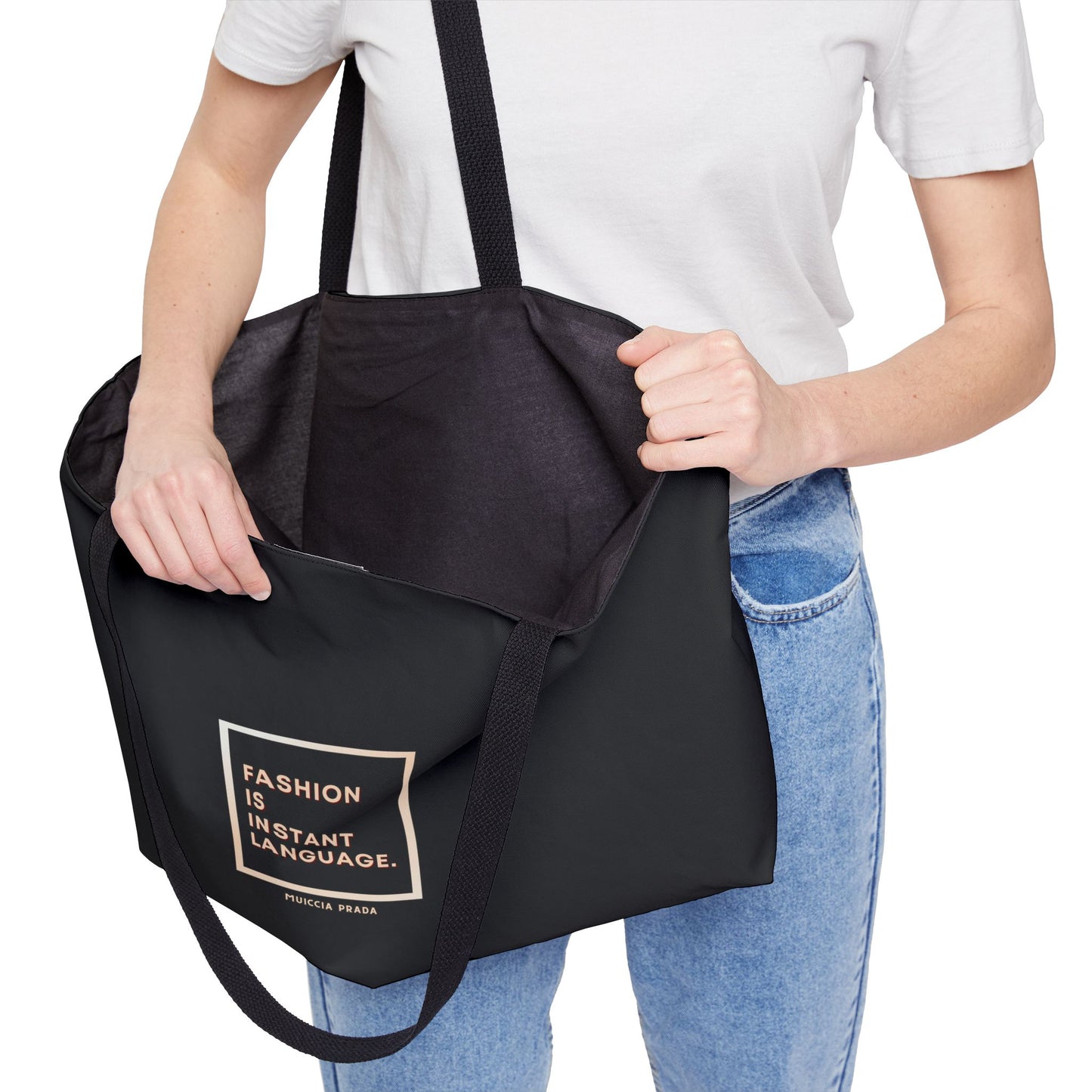 Person holding a black tote bag with text on a white background