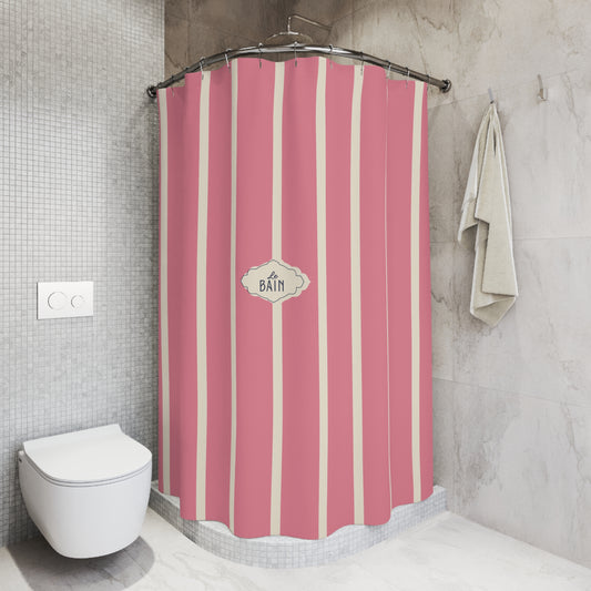Pink and cream vertical striped shower curtain in a modern tiled bathroom, featuring a central decorative label that reads 'BATH'.