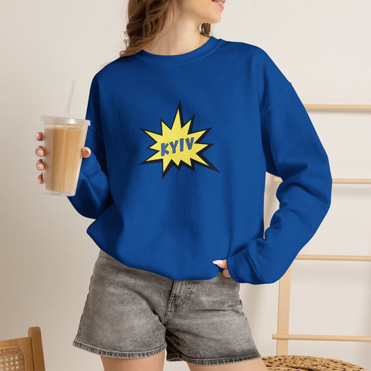 Person wearing a blue sweatshirt with a yellow 'KYIV' design, holding a drink.