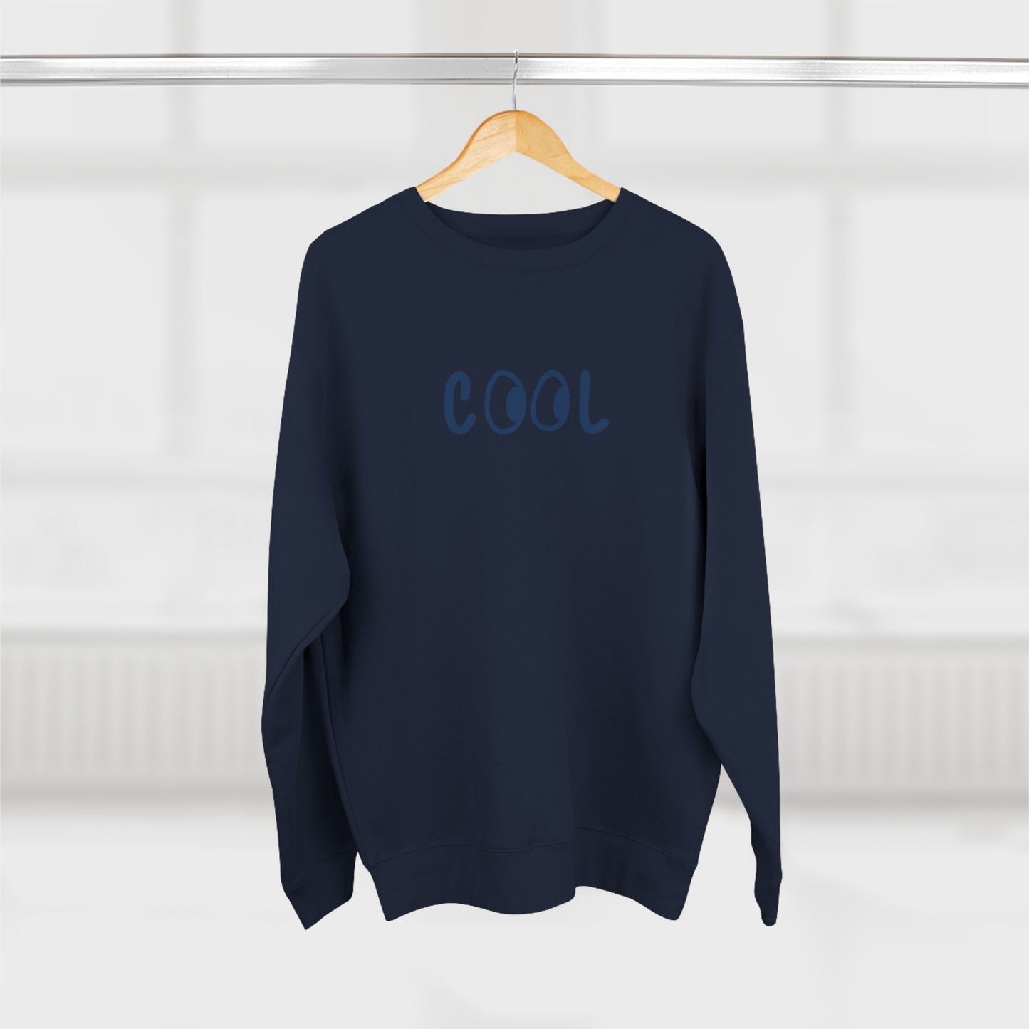 Navy blue sweater with 'COOL' text on a wooden hanger against a white background