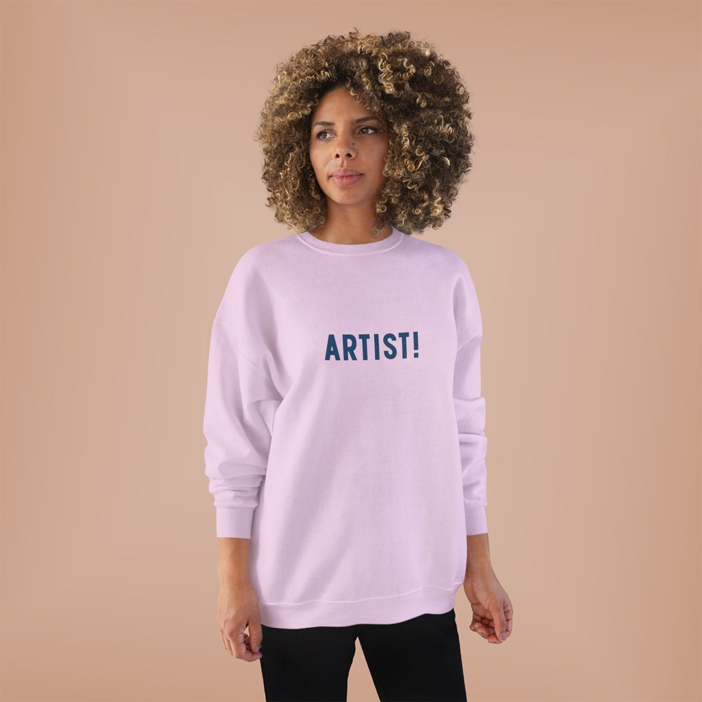 Person wearing a light purple sweatshirt with 'ARTIST!' text on a beige background