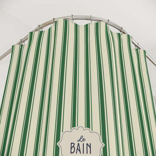 A green and cream vertically striped shower curtain with a silver metal rod and hooks, featuring a decorative label that reads 'Le BAIN'.