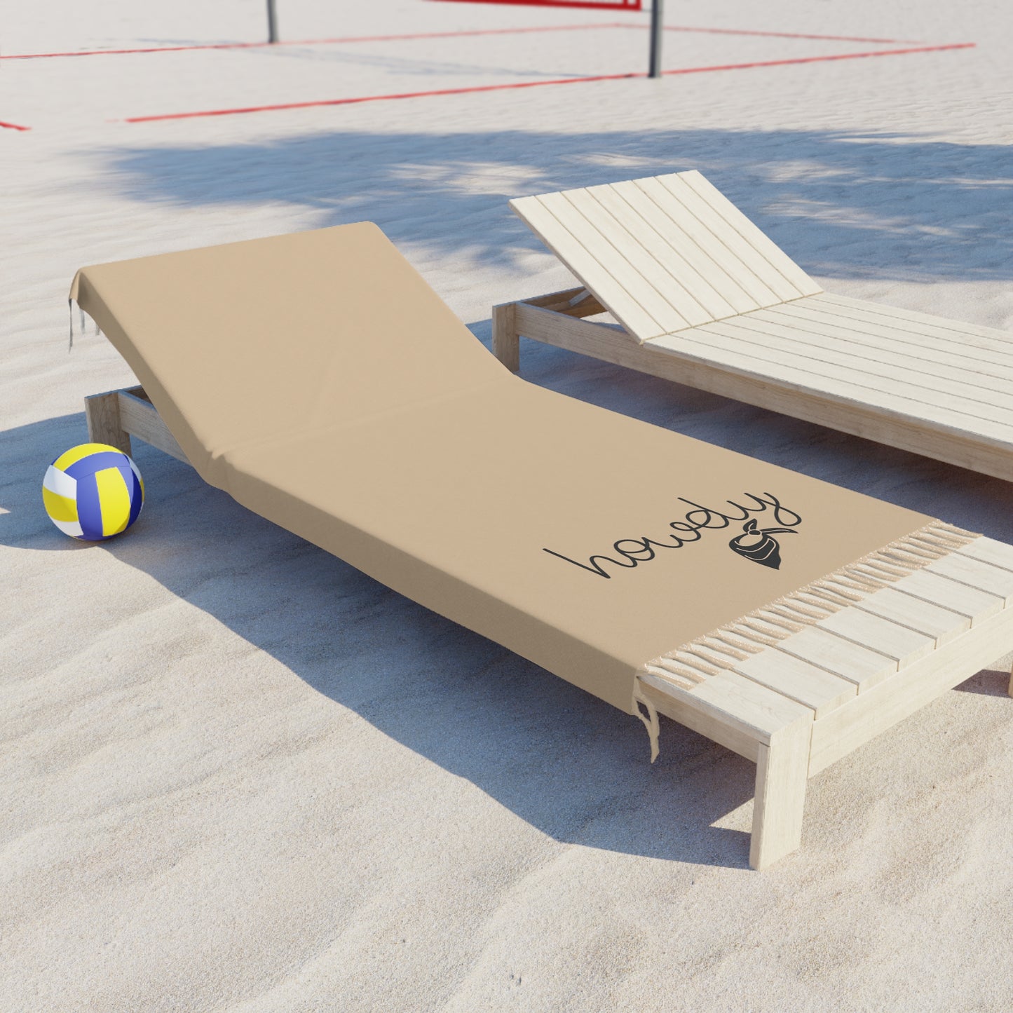 Beach lounge chair with a towel and volleyball on sand, 'howdy' logo visible