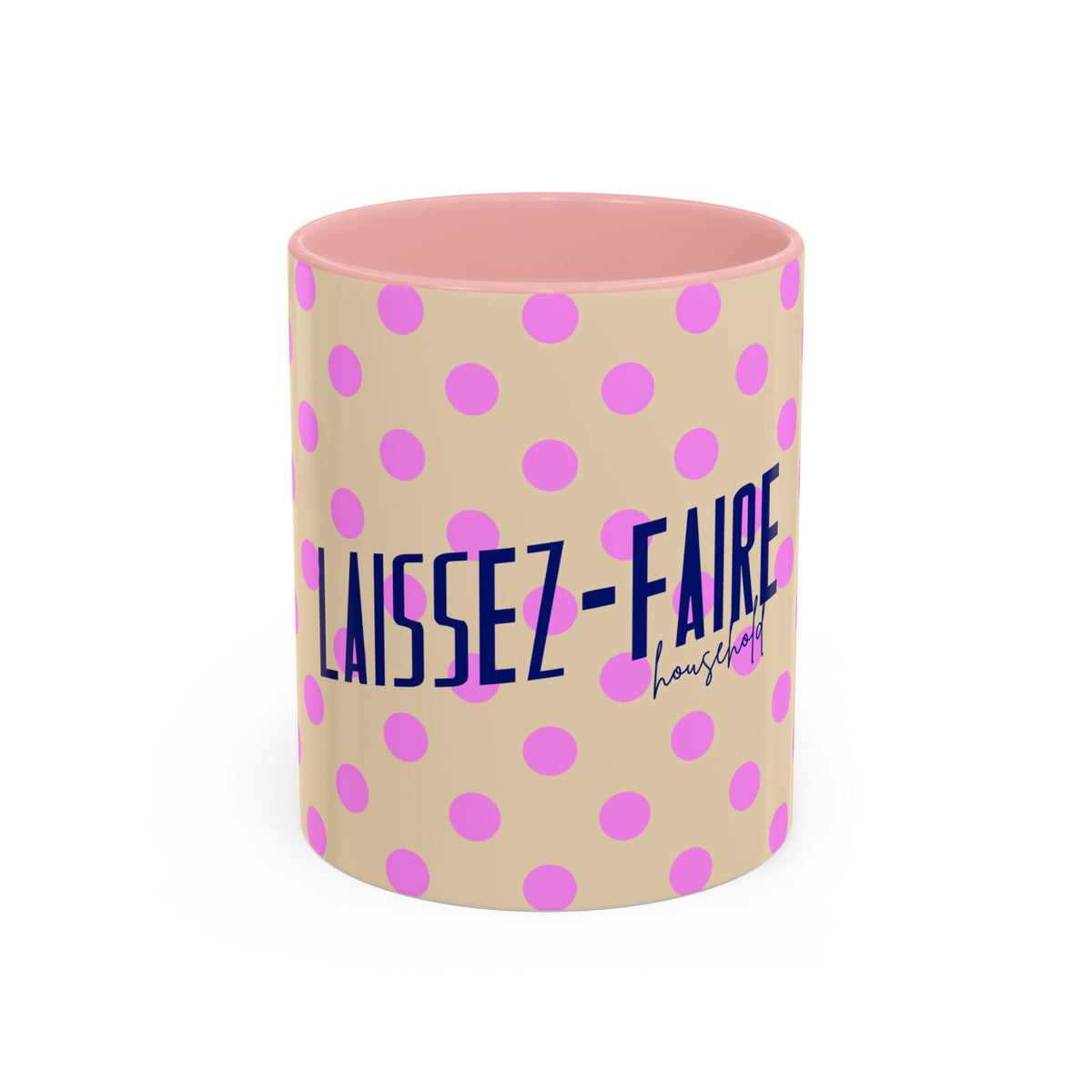A ceramic mug with a beige exterior patterned with pink polka dots, featuring the French text 'LAISSEZ-FAIRE' in navy blue and a pink heart, with a pink interior.