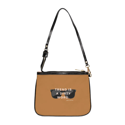 A small brown shoulder bag with a black strap and a quote by Anna Wintour printed on the front.