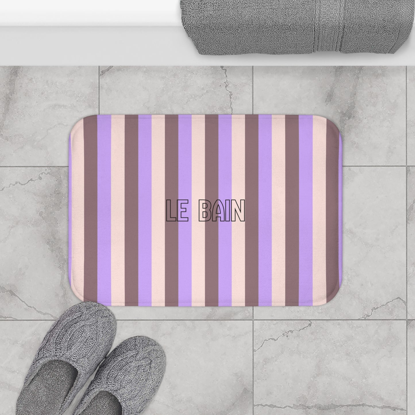 Striped bath mat with 'LE BAIN' text on a marble floor.