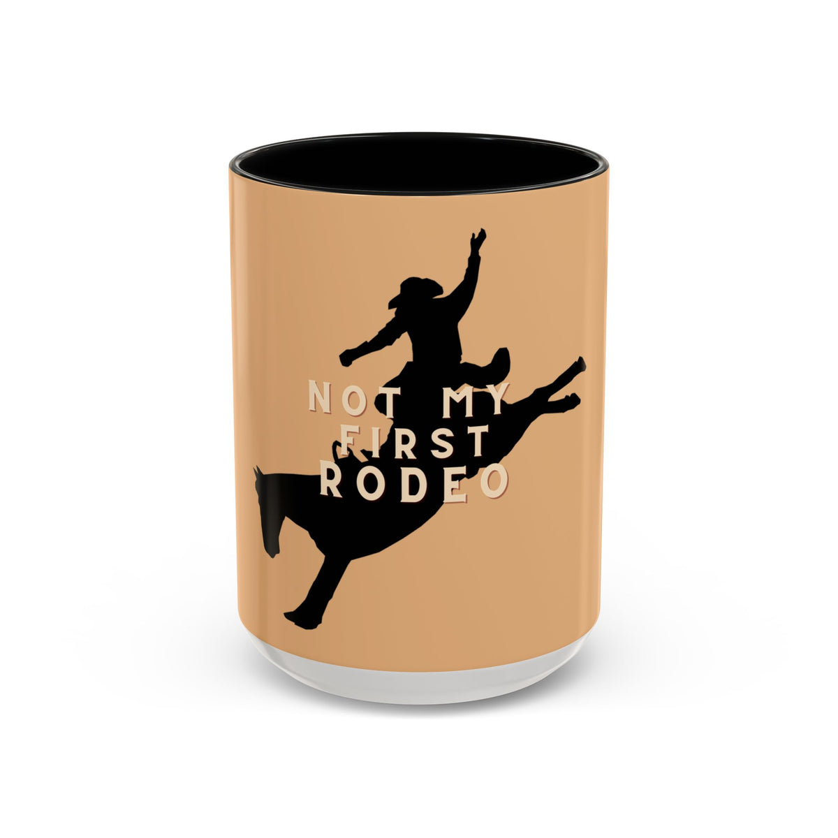 A ceramic mug with a warm tan exterior, black interior, and a black silhouette of a rider on a horse with the text 'NOT MY FIRST RODEO' in white and black, shown on a white background.
