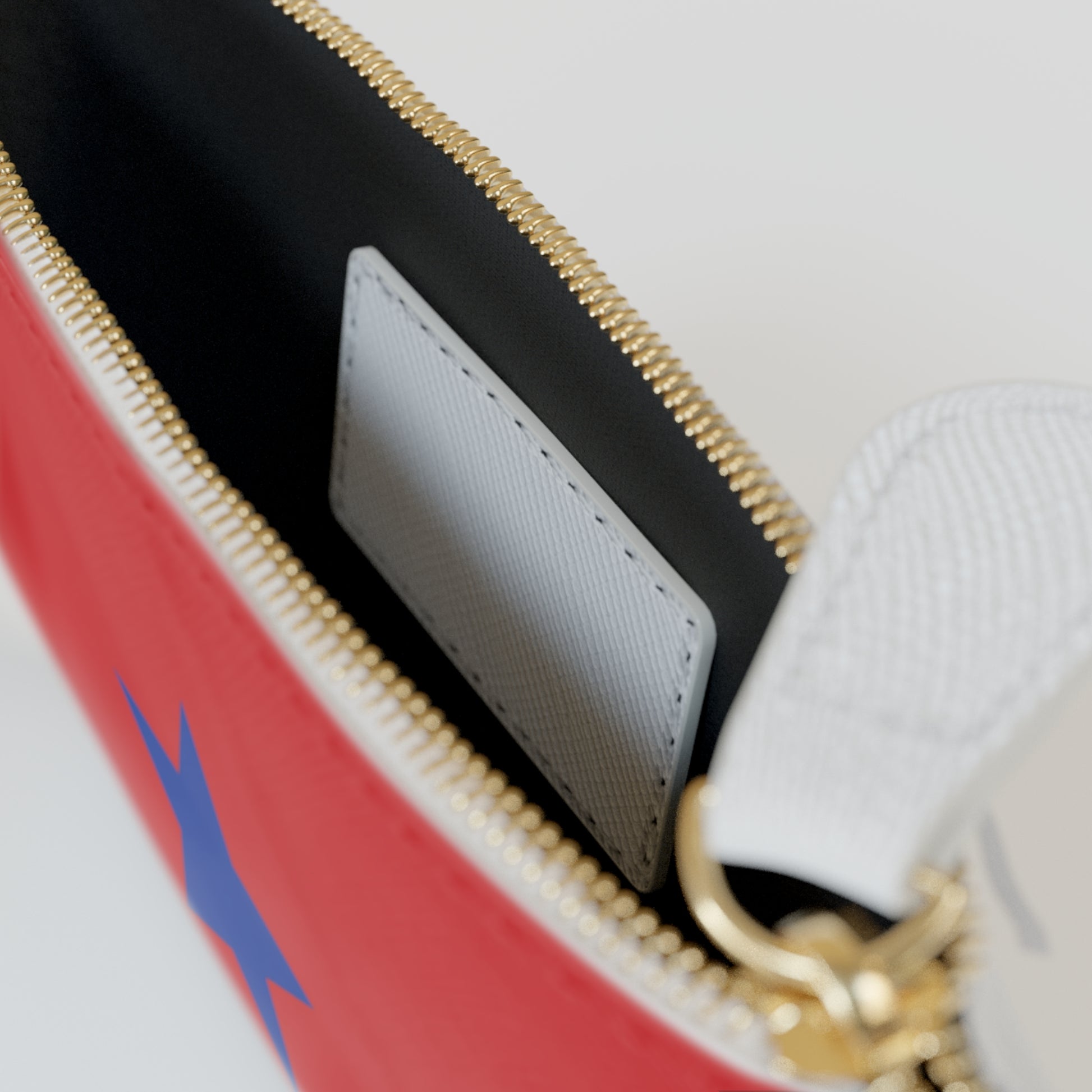 Close-up of a red bag with a gold zipper and a blue logo on a white background