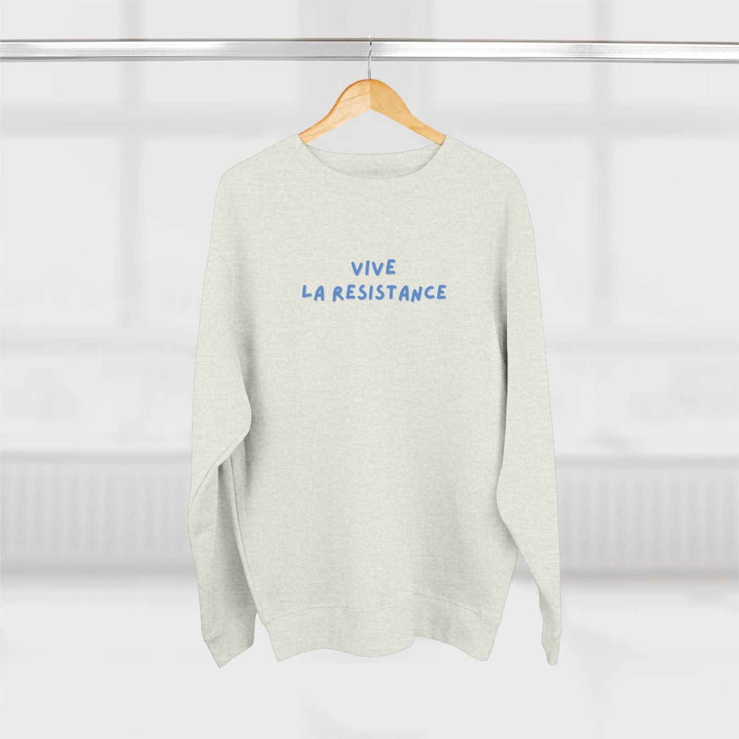 White sweater with 'Vive La Resistance' text on a hanger against a white background