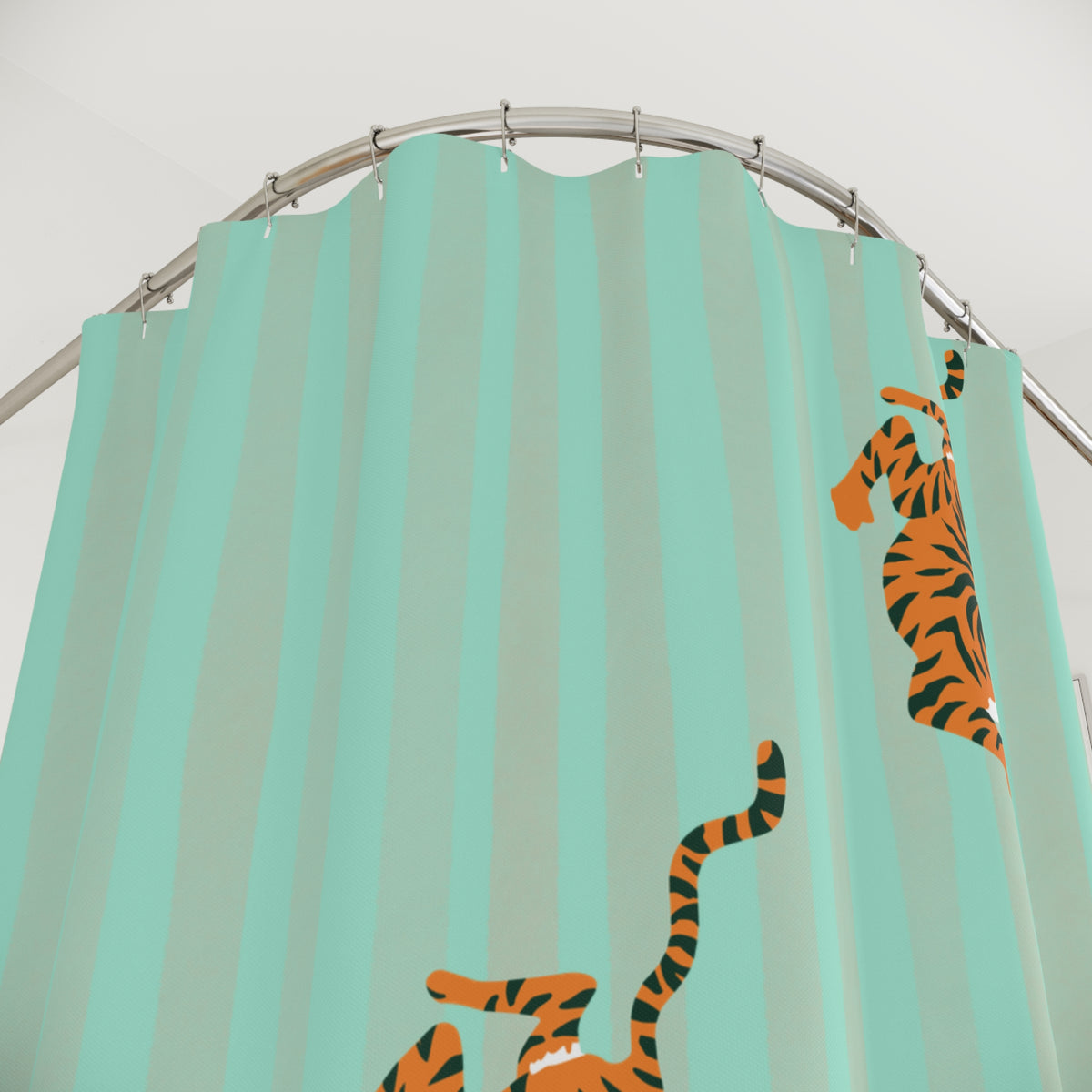A mint green shower curtain with vertical stripes and cartoon tiger illustrations, hanging from a curved metal rod against a white wall.