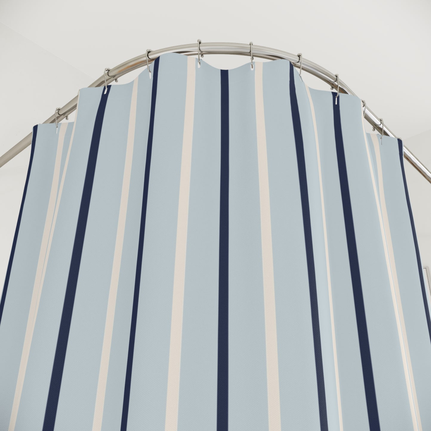 Striped shower curtain with blue and white vertical stripes on a metal rod against a light gray background.