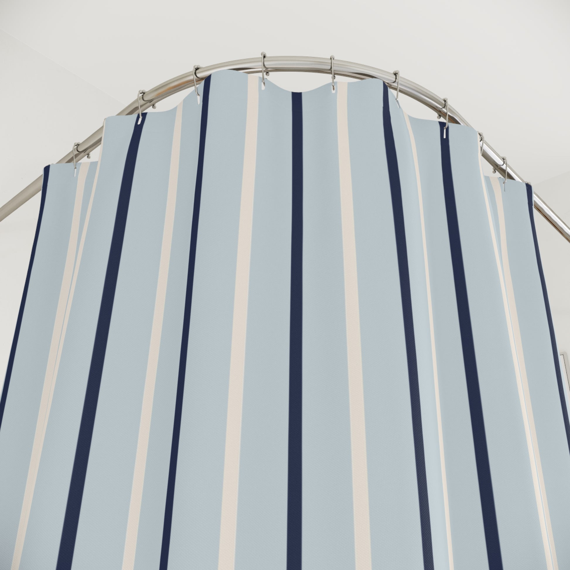 Striped shower curtain with blue and white vertical stripes on a metal rod against a light gray background.