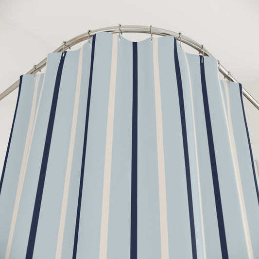 Striped shower curtain with blue and white vertical stripes on a metal rod against a light gray background.