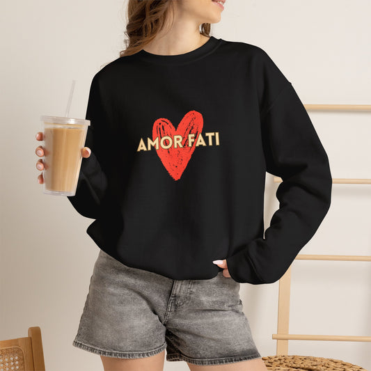 A woman wearing a black crewneck sweatshirt with a red heart graphic and the text 'AMOR FATI' in gold, paired with gray denim shorts and holding an iced coffee.