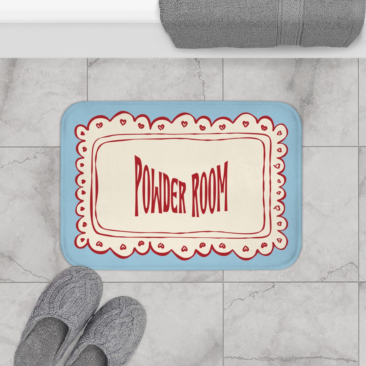 Doormat with 'Powder Room' text on a marble floor with slippers and a towel.
