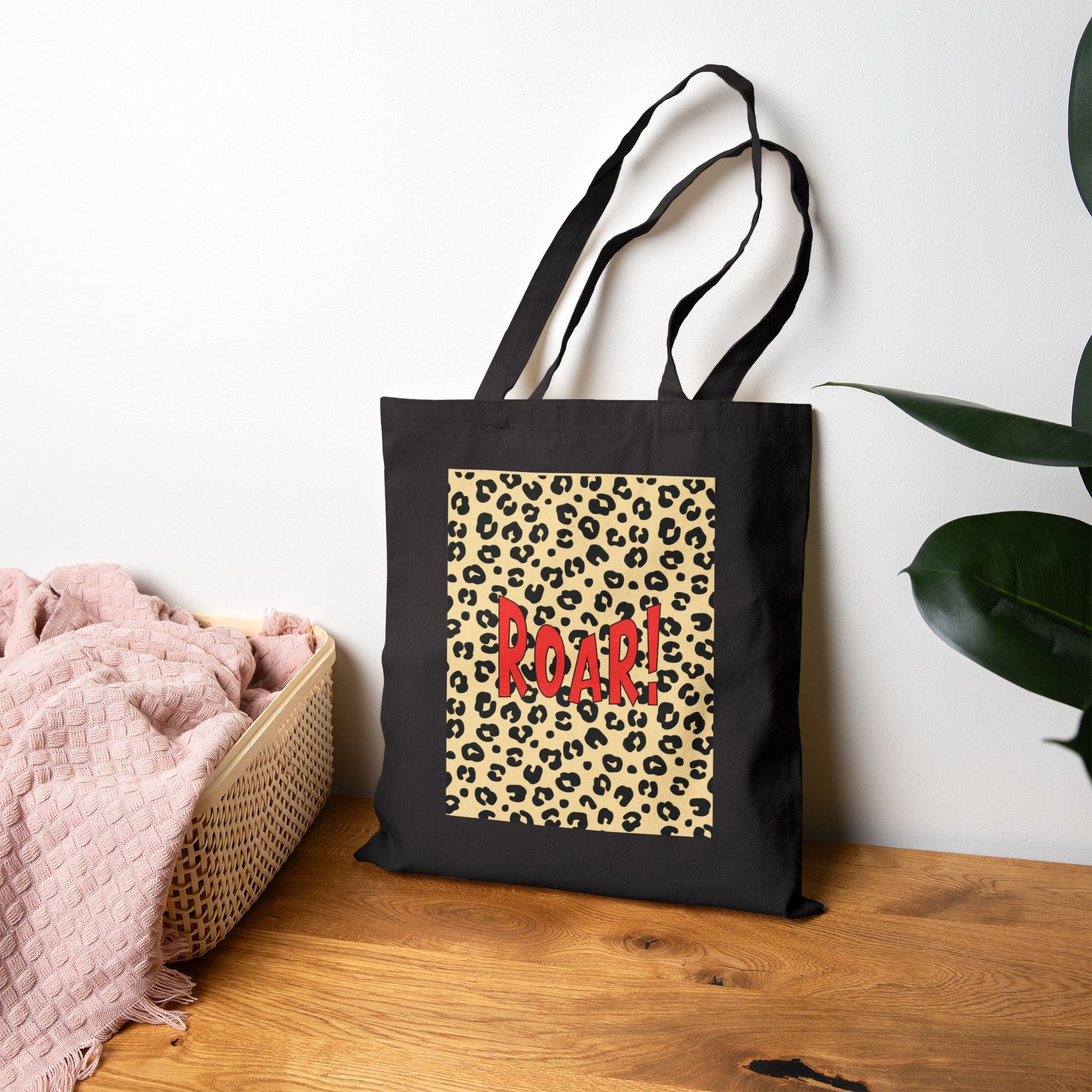 Black tote bag with leopard print and 'ROAR!' text on a wooden surface.