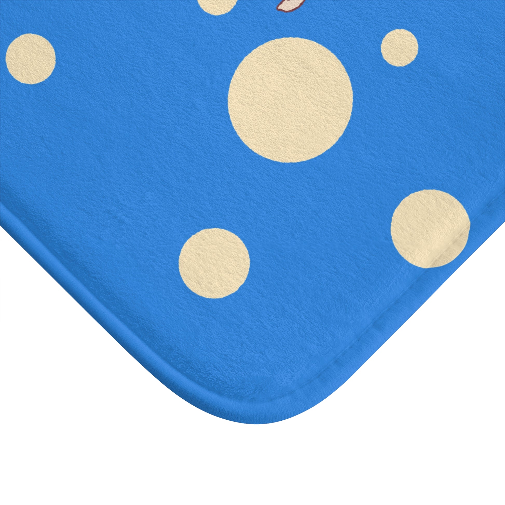 A close-up of a blue fabric product, likely a blanket or cushion cover, featuring a pattern of large and small beige polka dots, shown against a plain white background.