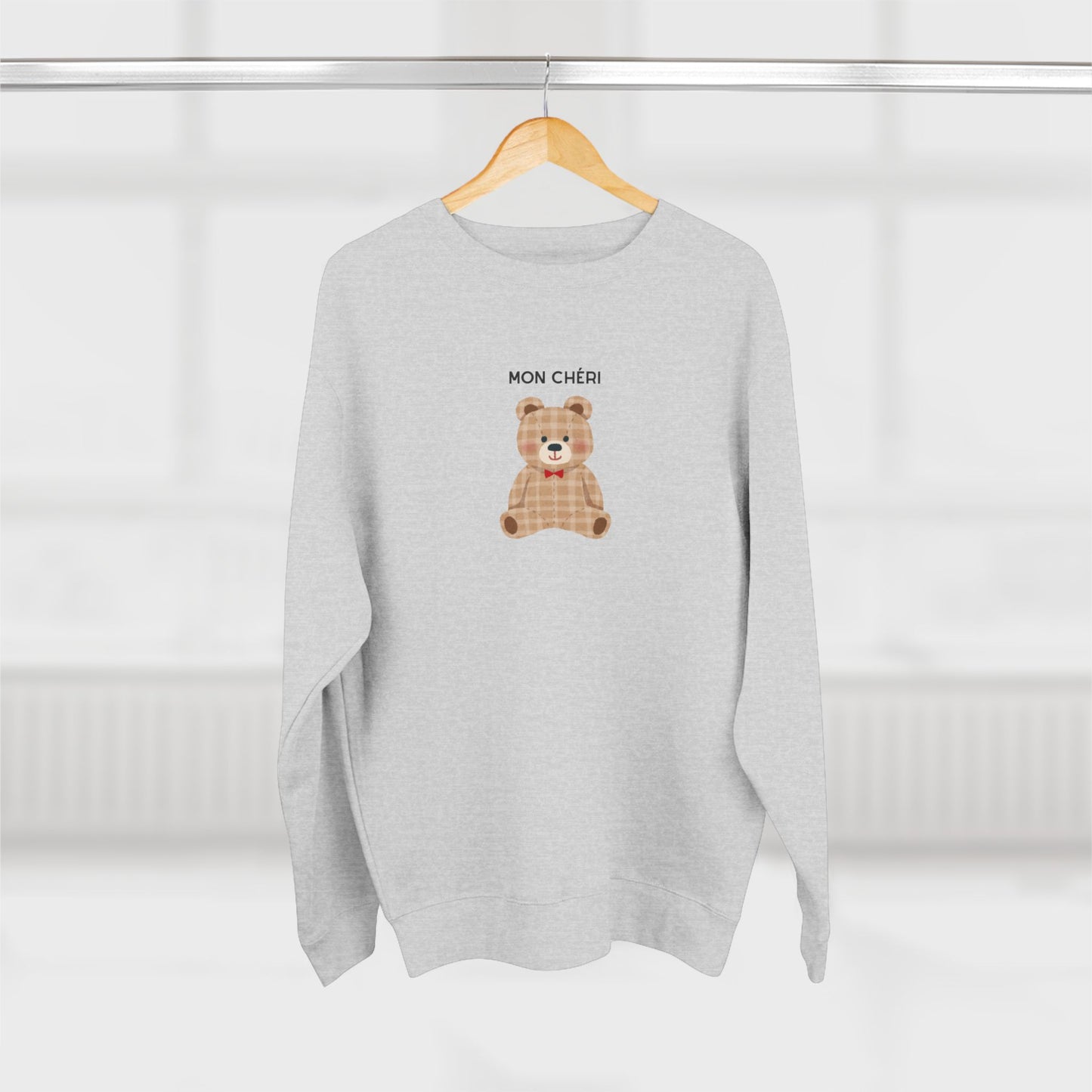 Gray sweatshirt with a teddy bear design and 'MON CHÓRI' text on a white background
