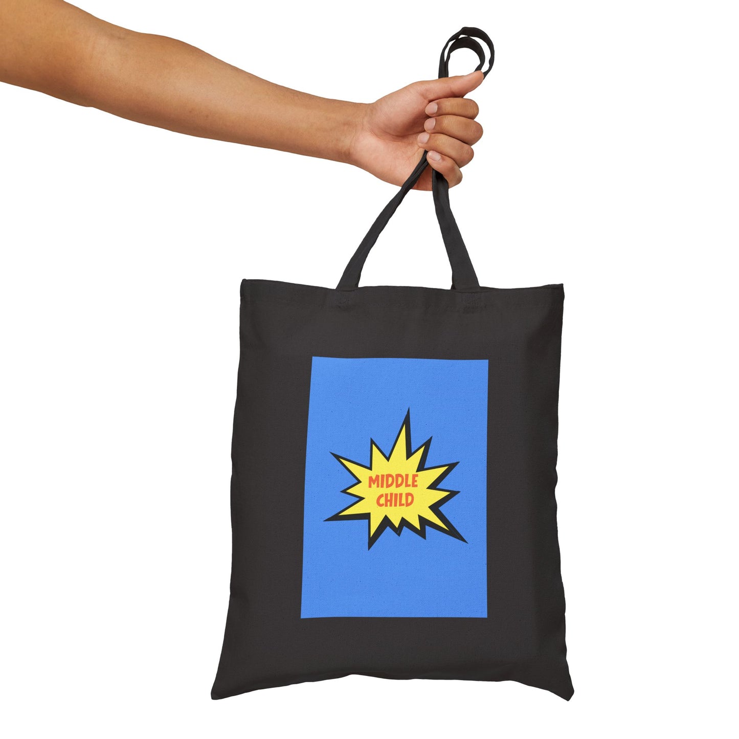 Black tote bag with a blue square and yellow 'Middle Child' graphic held by a hand on a white background