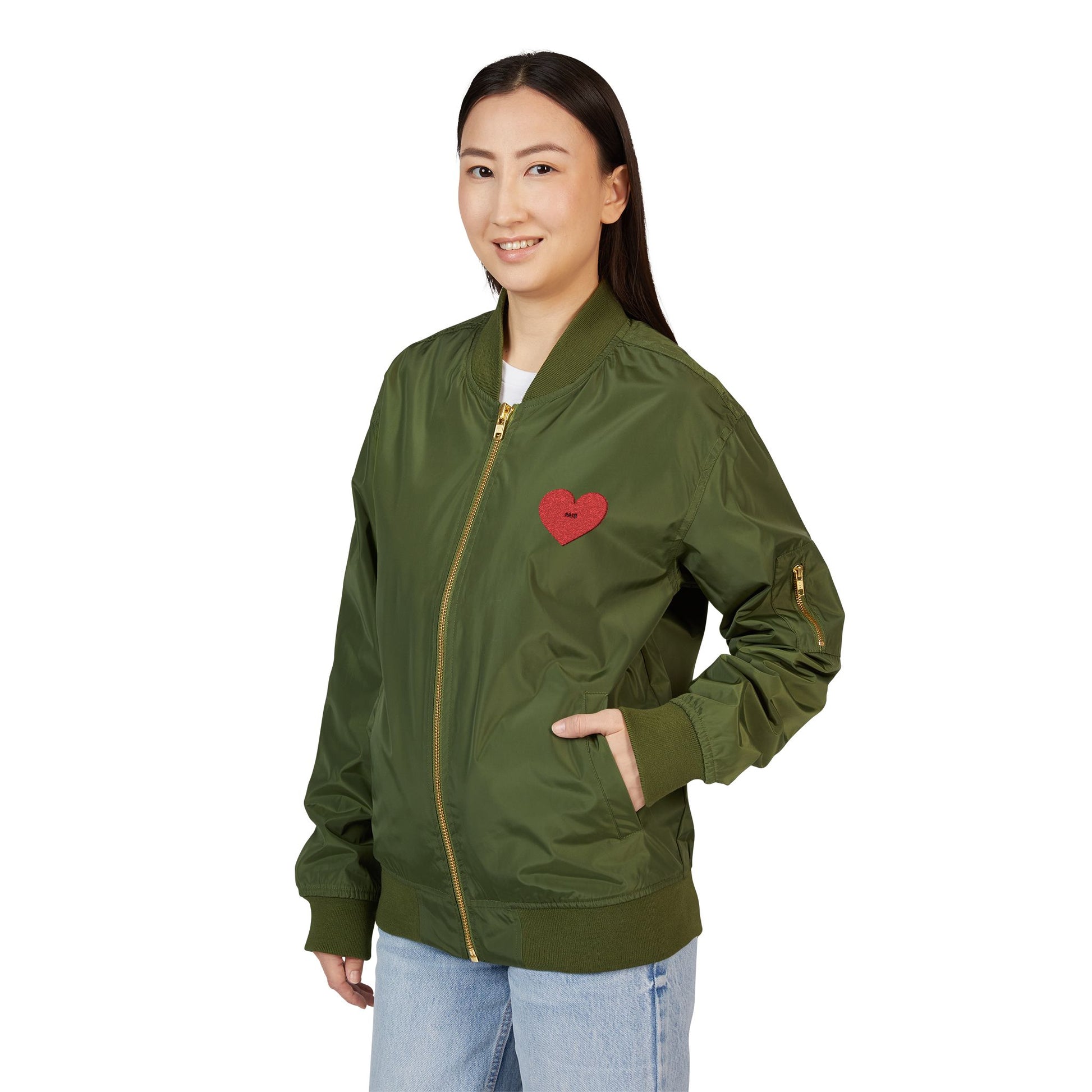 Woman wearing a green bomber jacket with a red heart emblem on a white background