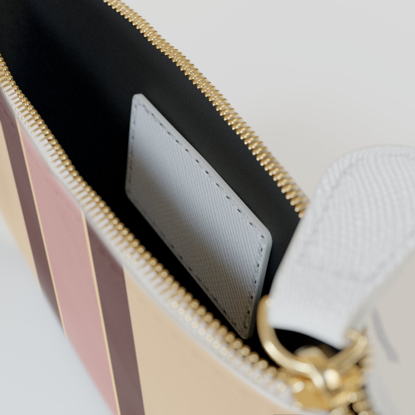 Close-up of a handbag with gold zipper and pink and beige design on a light gray background