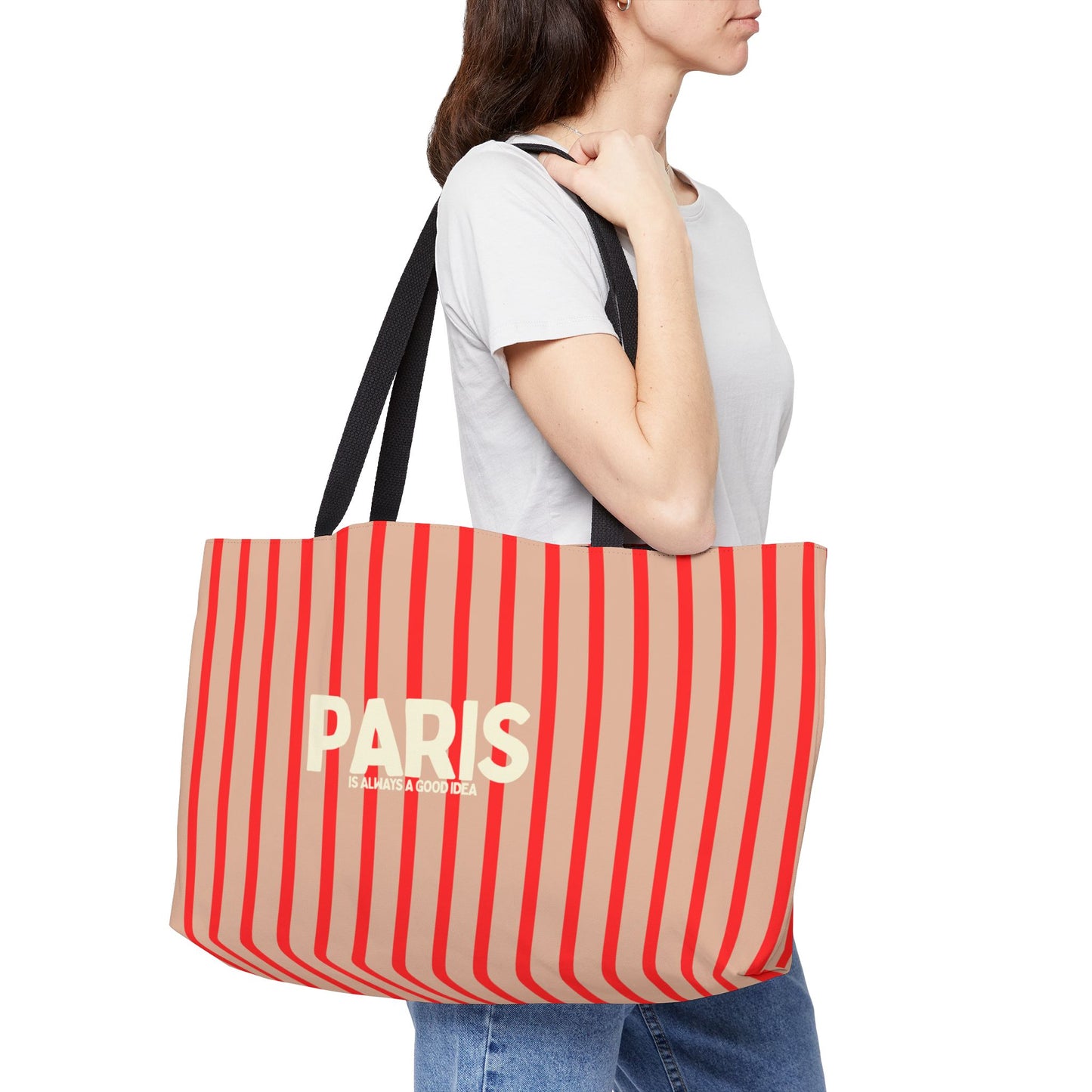 Person holding a red and beige striped bag with 'PARIS' text on a white background