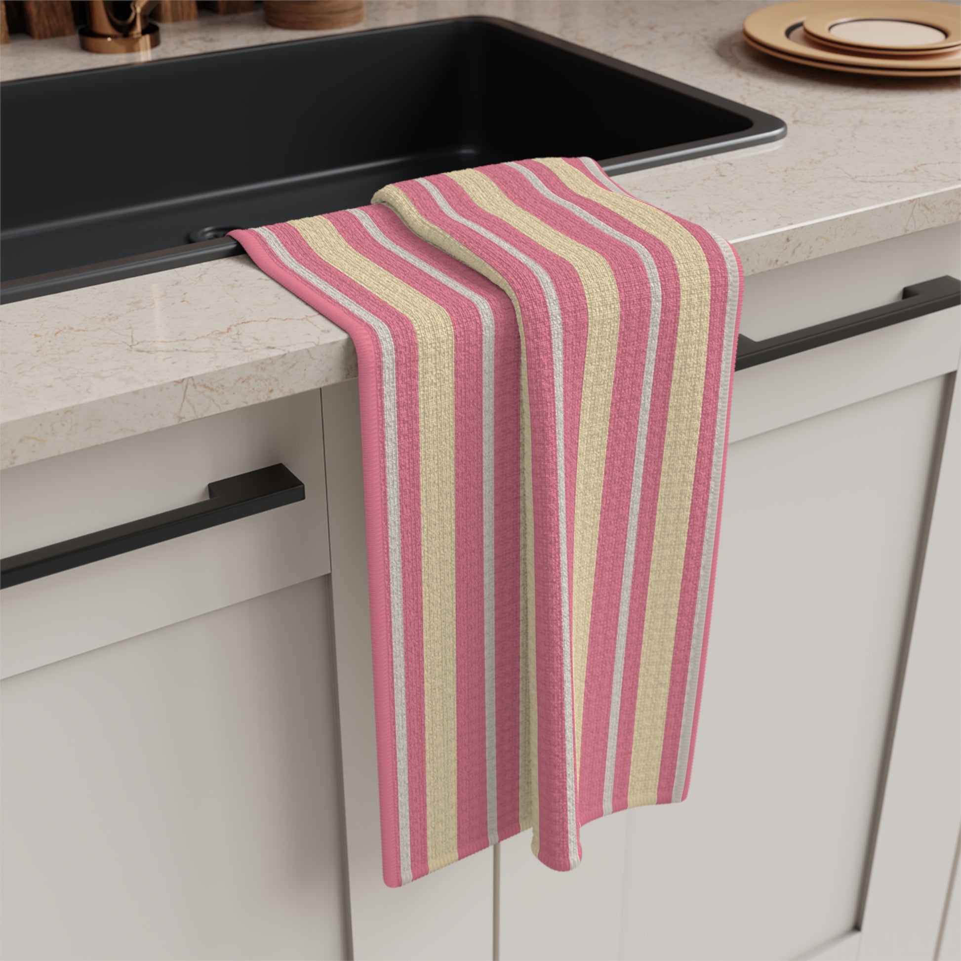 Striped pink and beige towel hanging on a kitchen cabinet handle.