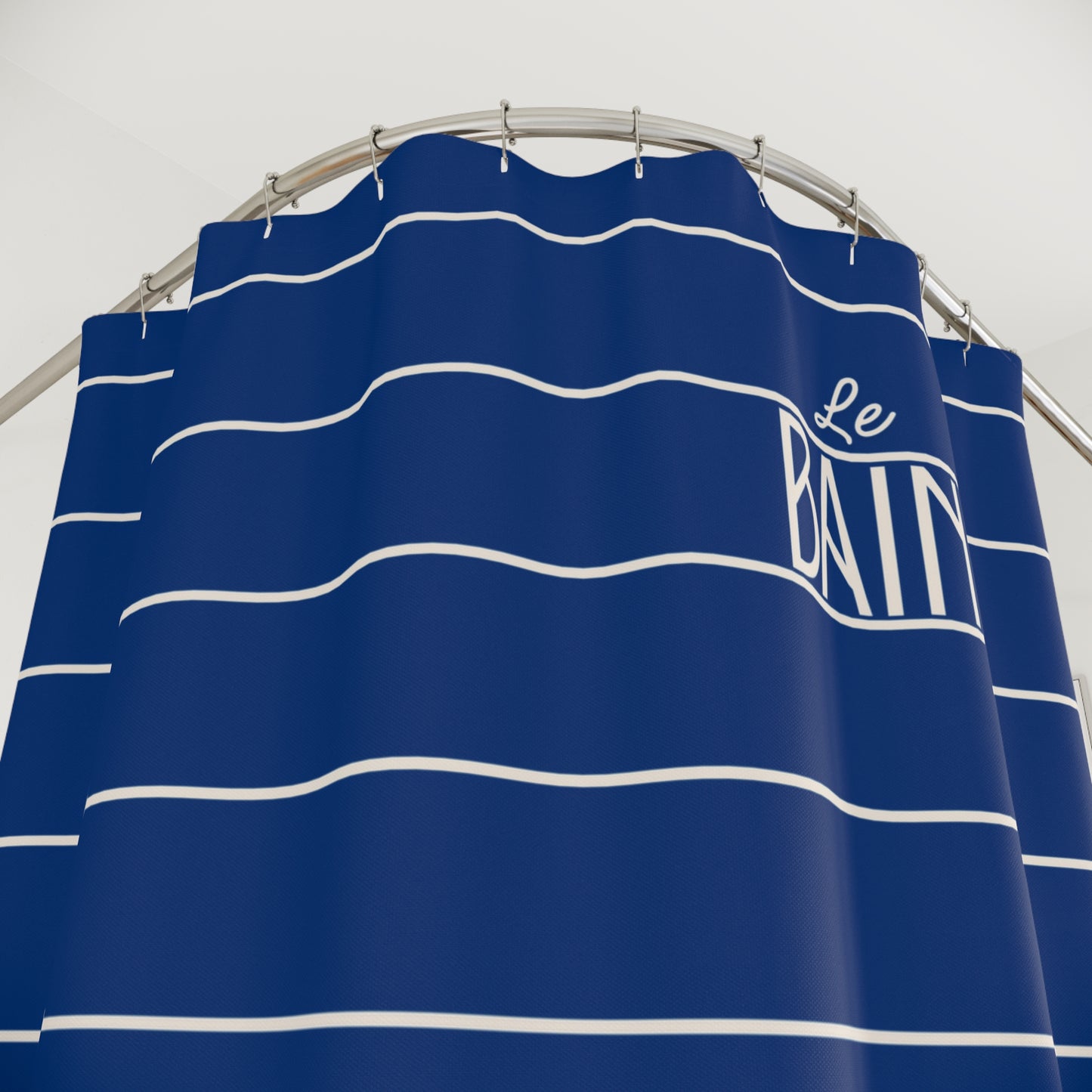 Blue and white striped shower curtain with 'Le Bain' branding on a gray background