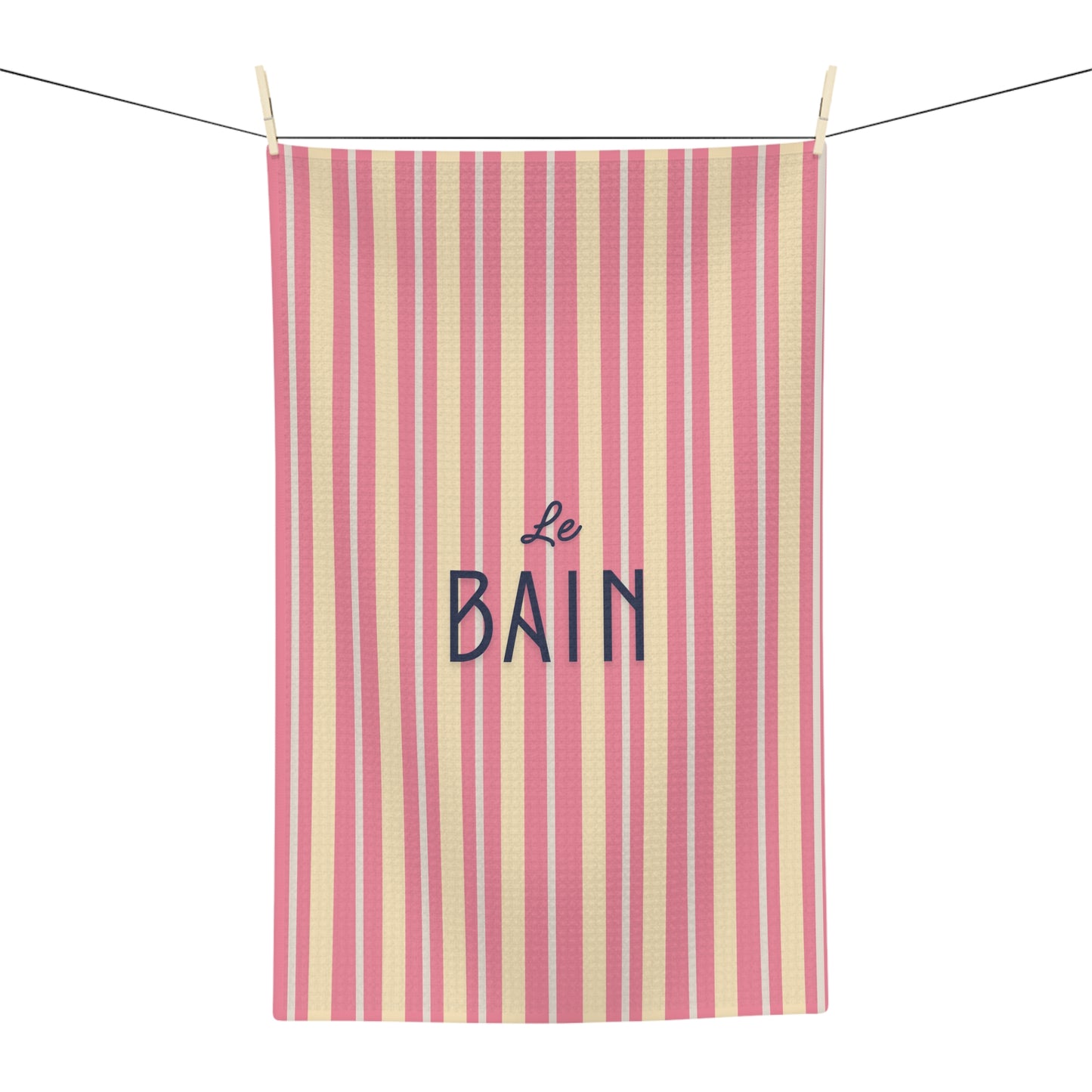 Striped towel with 'Le Bain' text hanging on a line