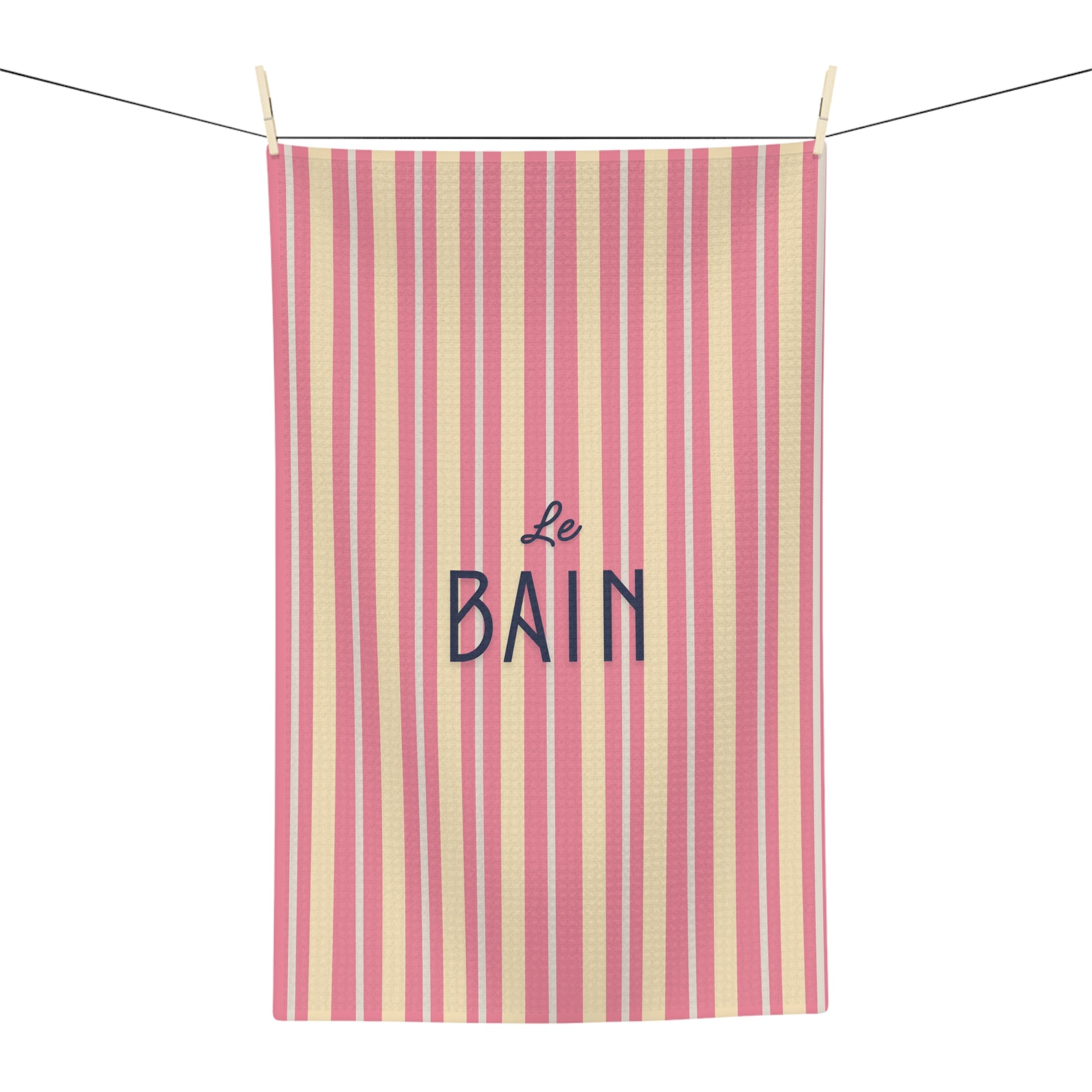 Striped towel with 'Le Bain' text hanging on a line