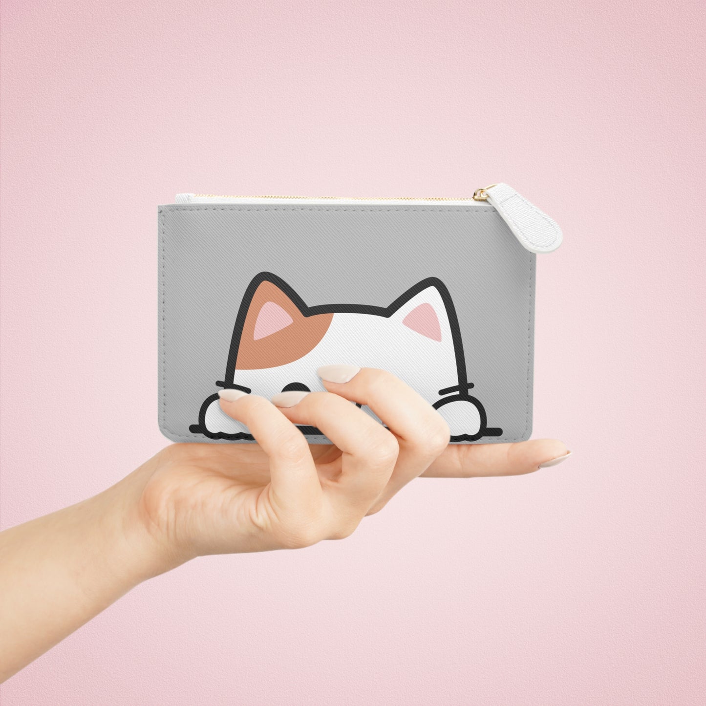 Gray pouch with a cat design held by a hand against a pink background