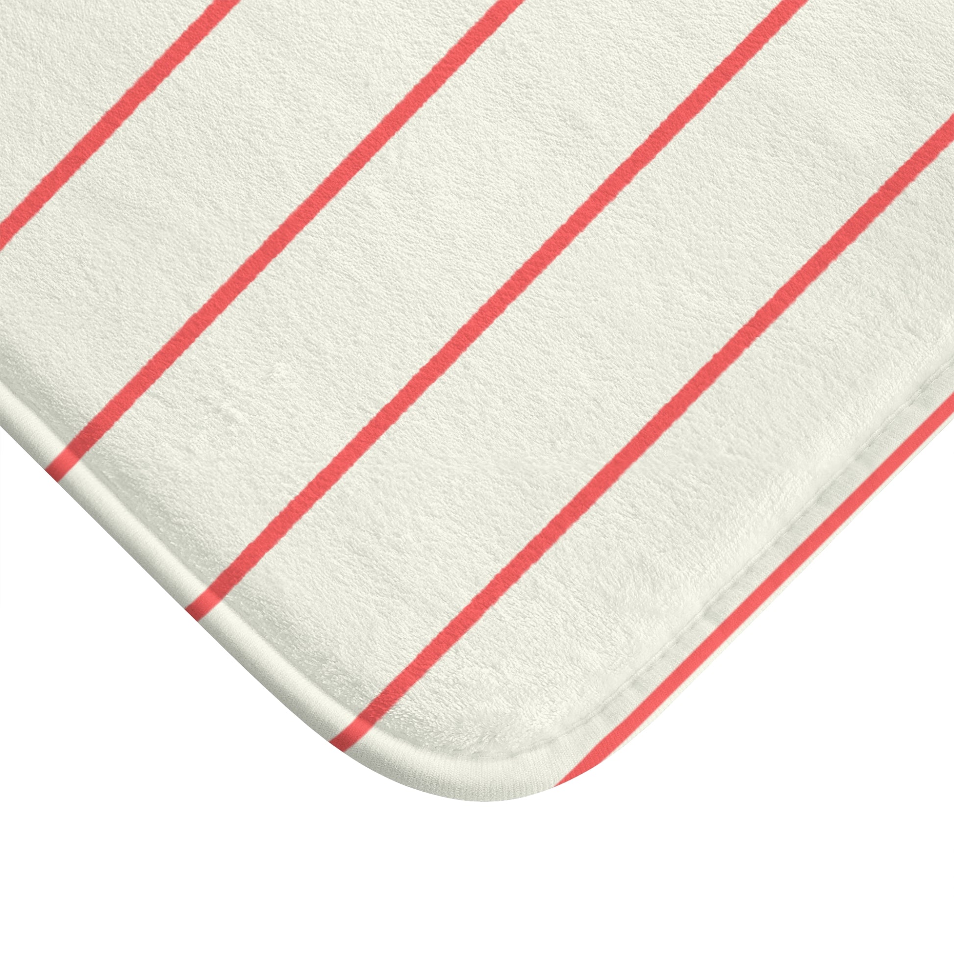 A close-up of a white or off-white textured fabric item with evenly spaced coral-red diagonal stripes, showing rounded corners and a stitched edge on a white background.