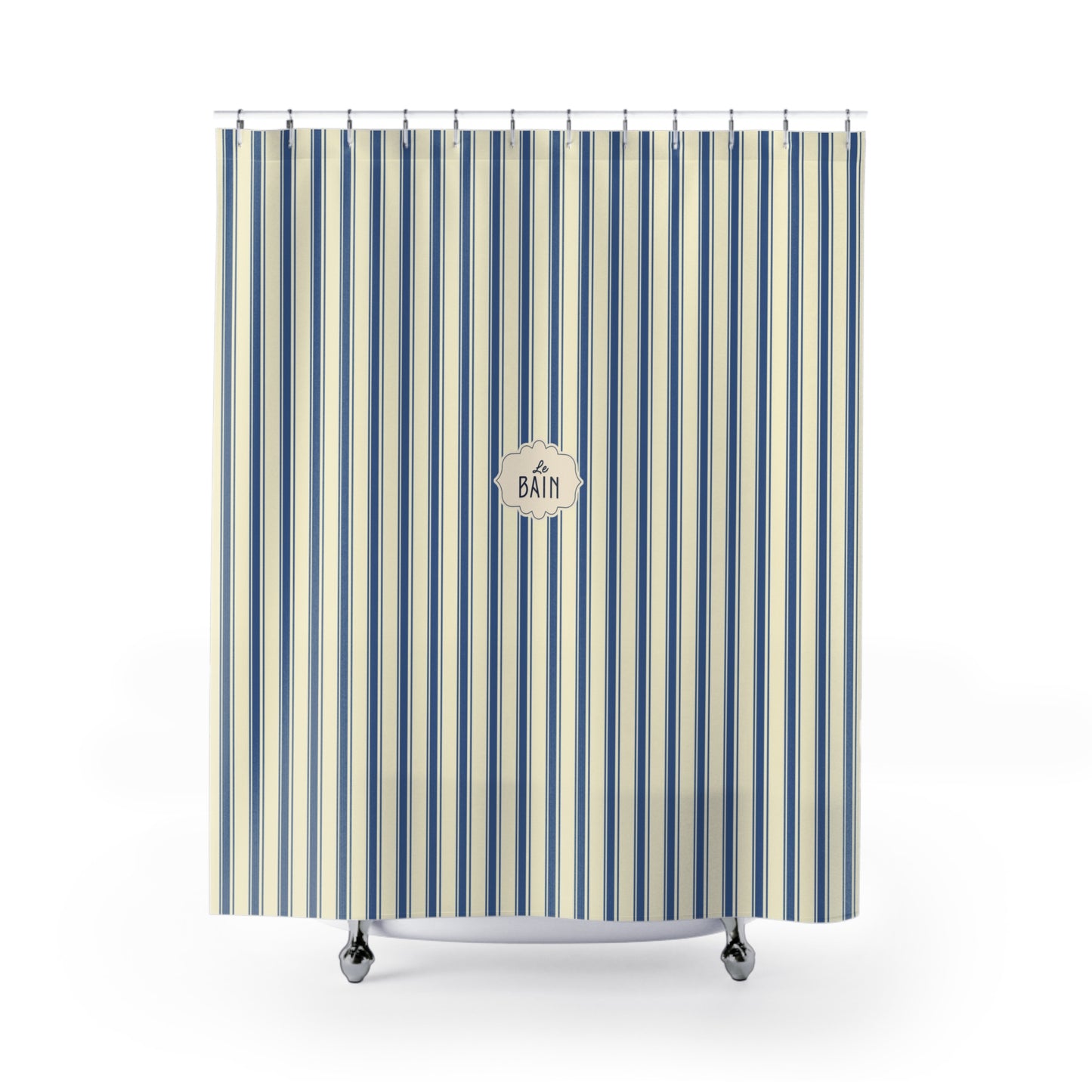 A striped shower curtain with vertical blue, navy, and cream stripes, featuring a circular 'BATH' logo in the center. The curtain is shown hanging from silver hooks over a white tub rim with silver feet, set against a plain white background.