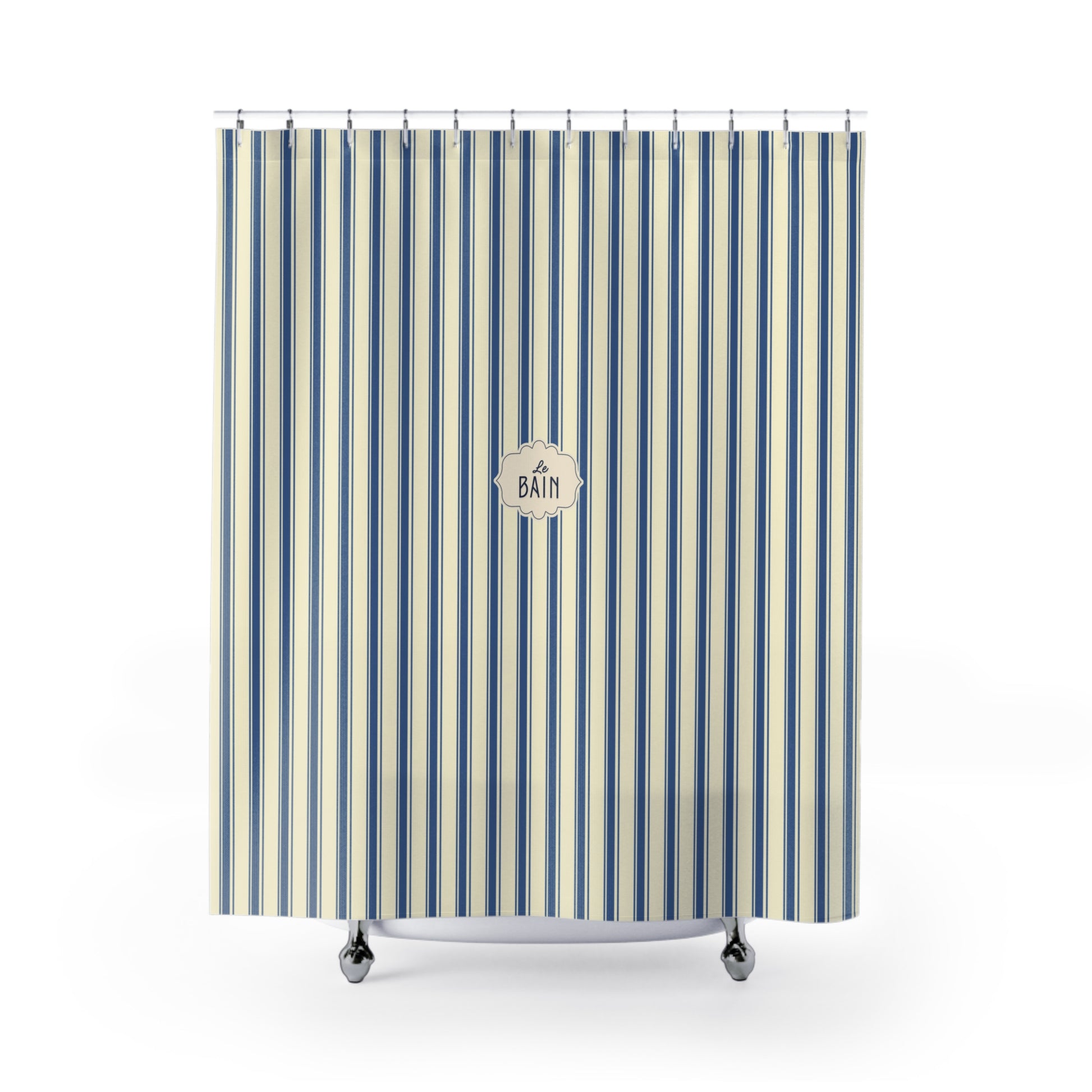 A striped shower curtain with vertical blue, navy, and cream stripes, featuring a circular 'BATH' logo in the center. The curtain is shown hanging from silver hooks over a white tub rim with silver feet, set against a plain white background.