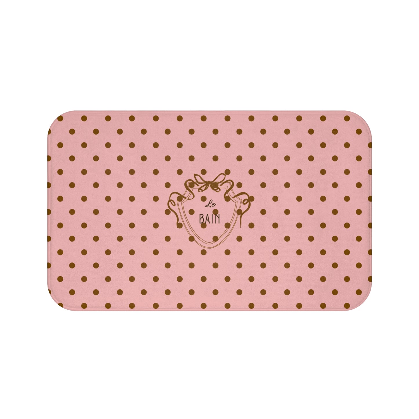 Pink bath mat with gold polka dots and a logo on a white background