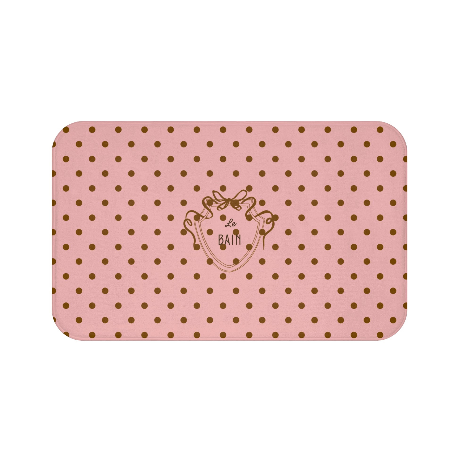 Pink bath mat with gold polka dots and a logo on a white background