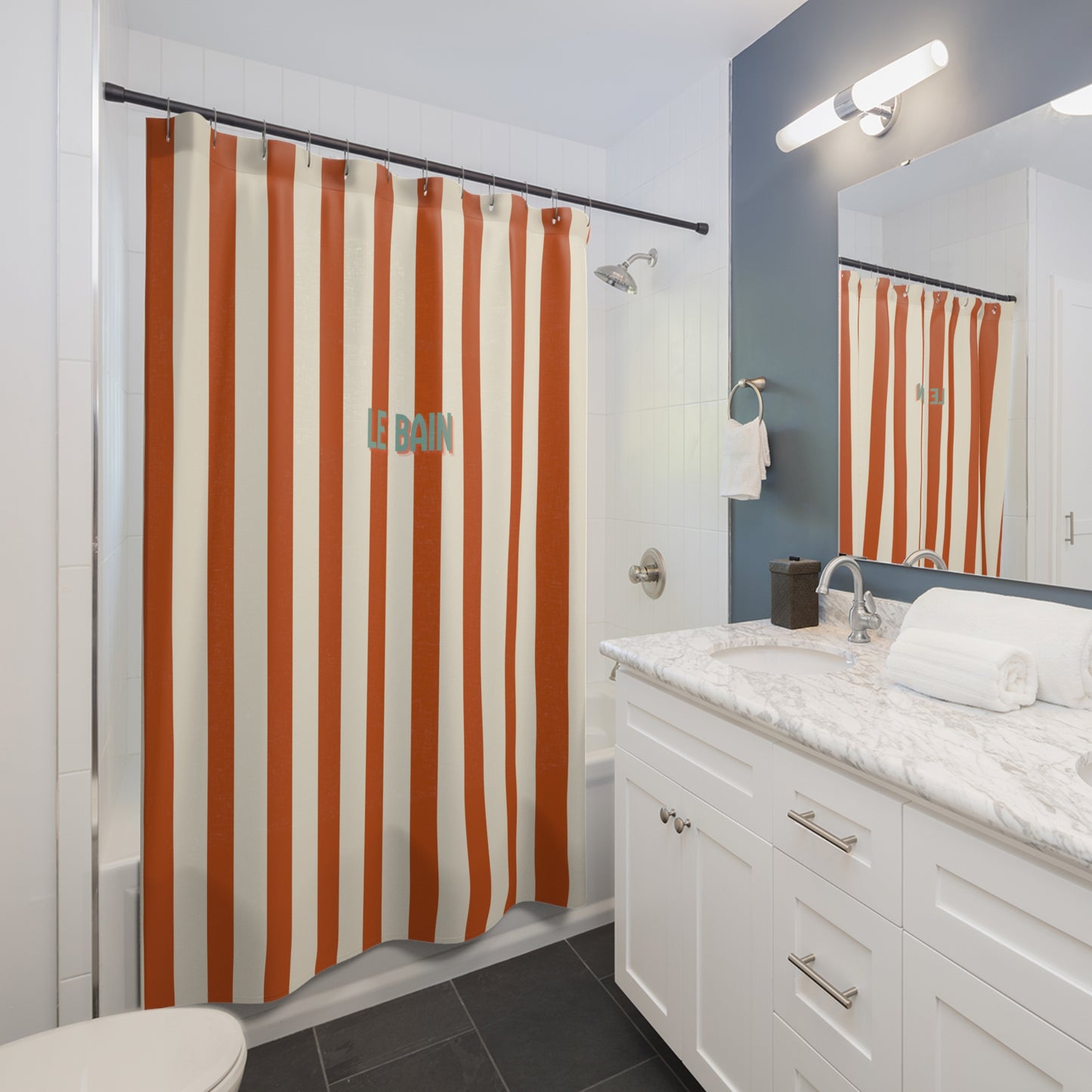 Bathroom with orange and white striped shower curtain, white vanity, and mirror.